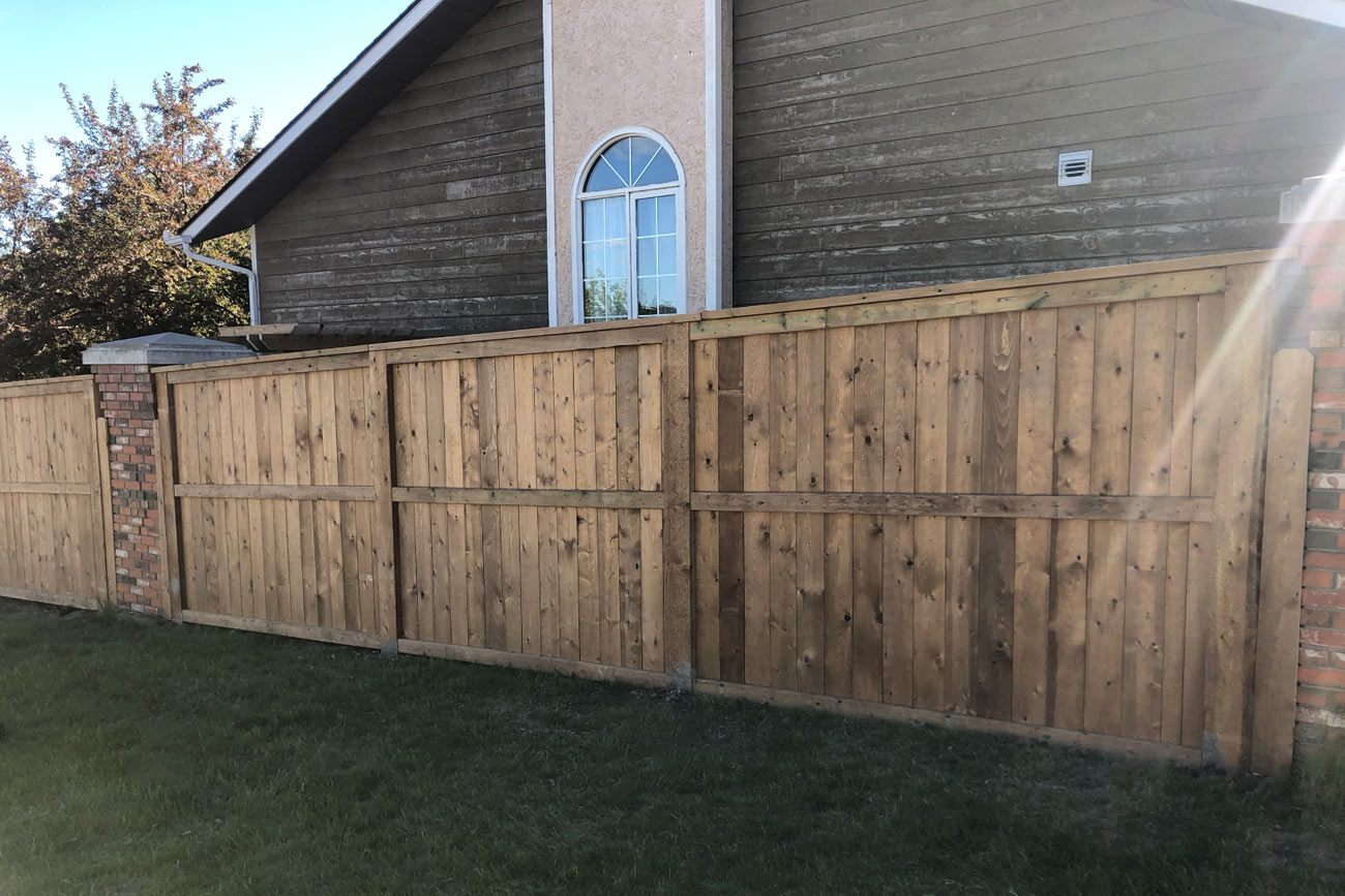 outdoor photo of a wooden fence with brick pillars