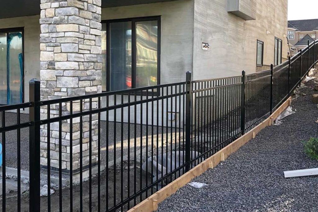 a black iron fence separating two houses