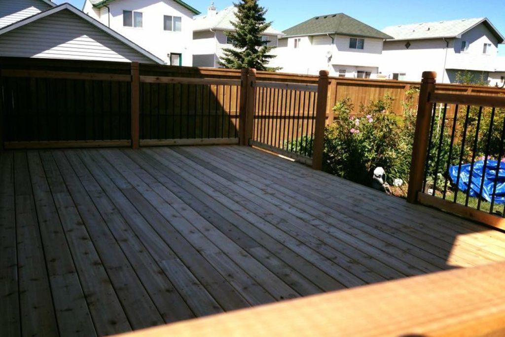 a wooden deck in a backyard surrounded by neighbouring houses